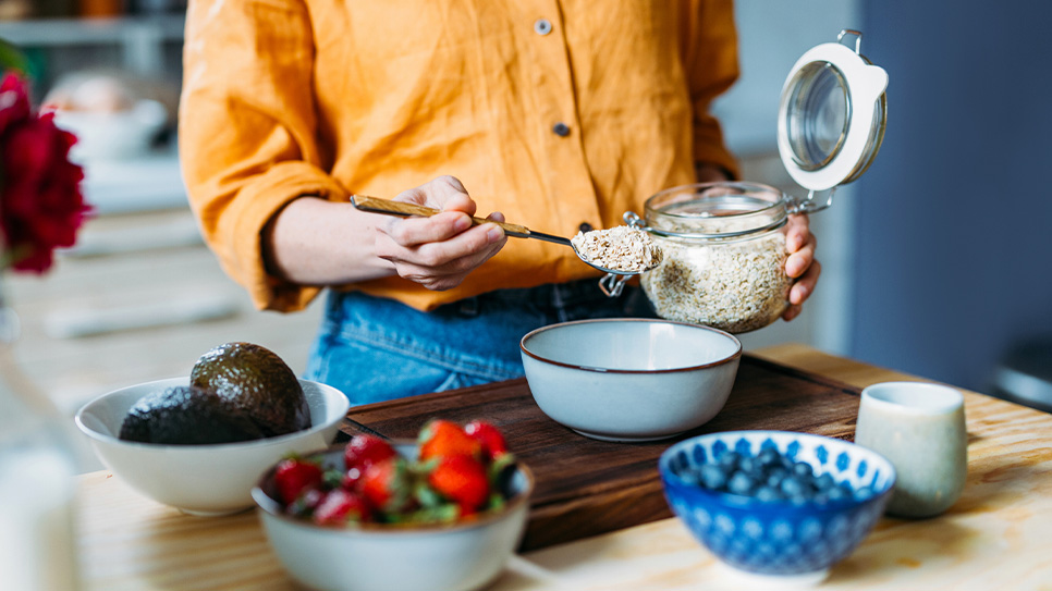 A woman pouring oats into a bowl.