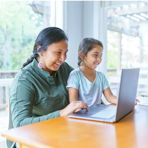 a woman and a girl looking at a laptop