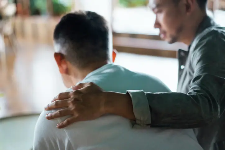 a man holding another man's shoulder