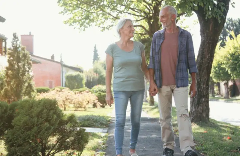 a man and woman holding hands and walking on a path