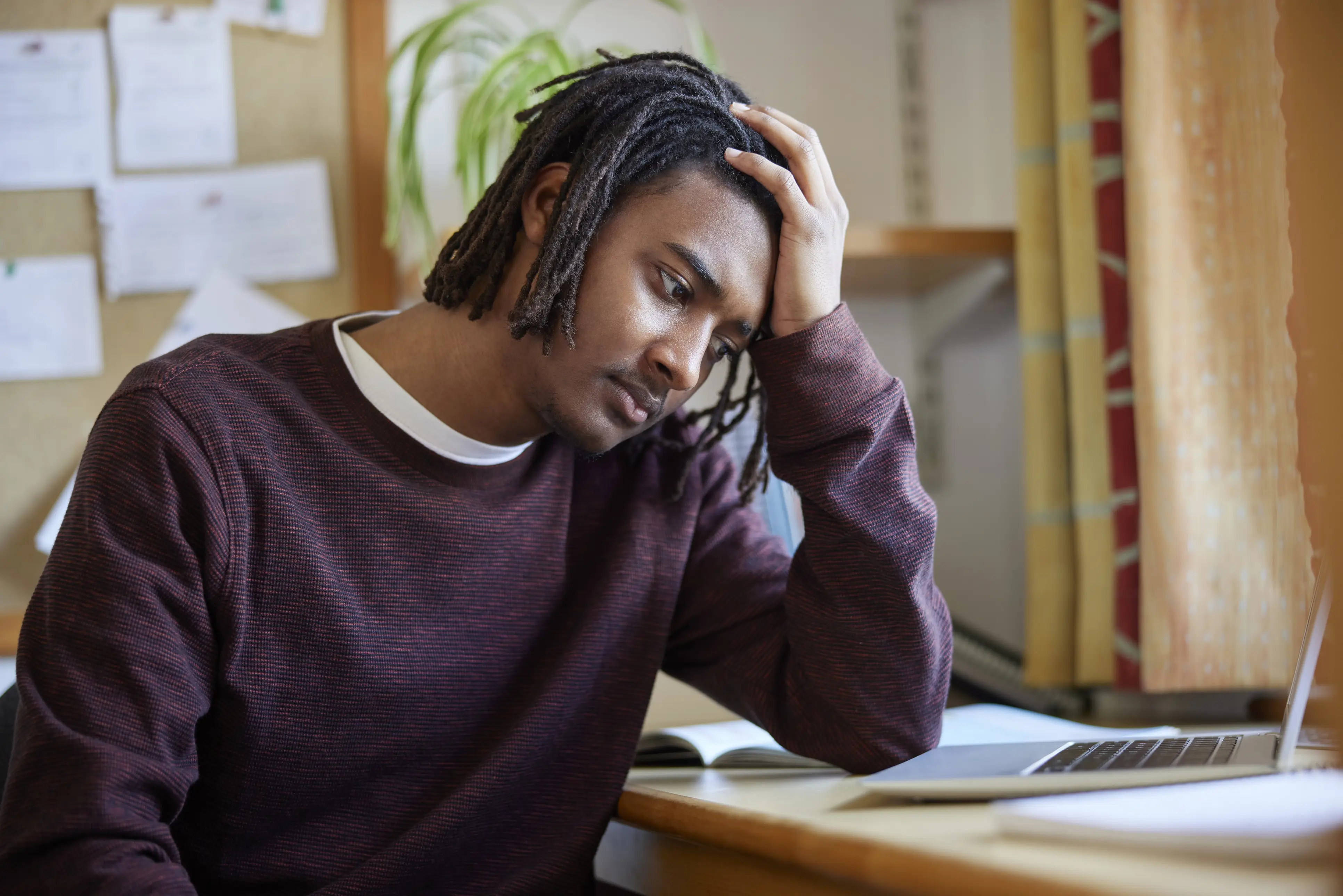 a man with his hand on his head looking at a laptop