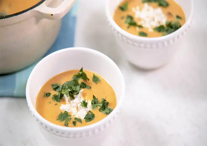 two cups of soup with parsley and cheese