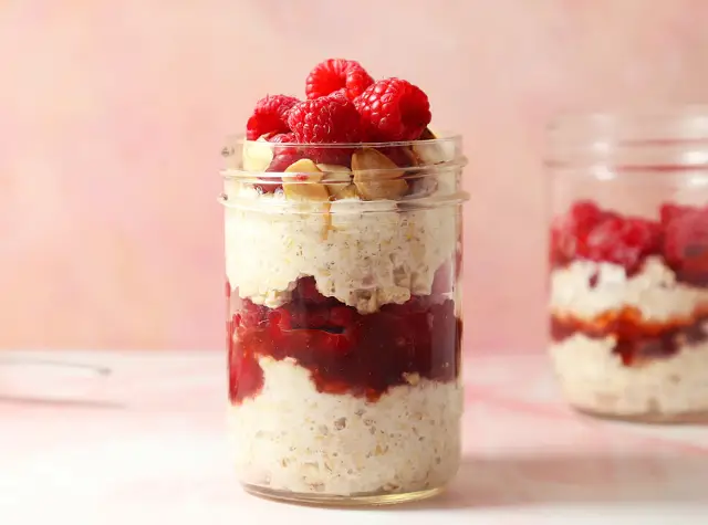 a jar of oatmeal with raspberries and nuts