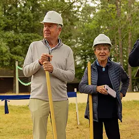 a man and woman in hardhats holding shovels