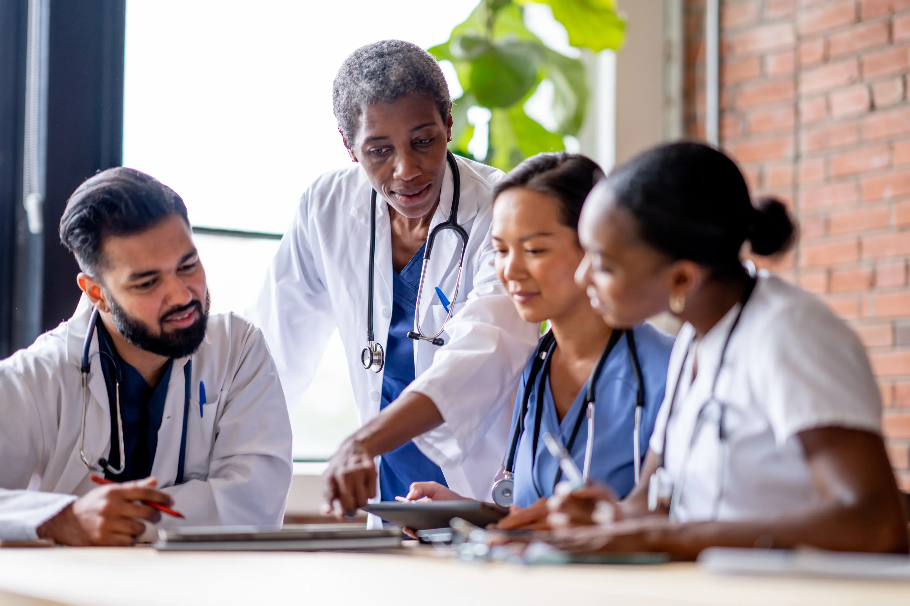 a group of people in lab coats looking at a tablet