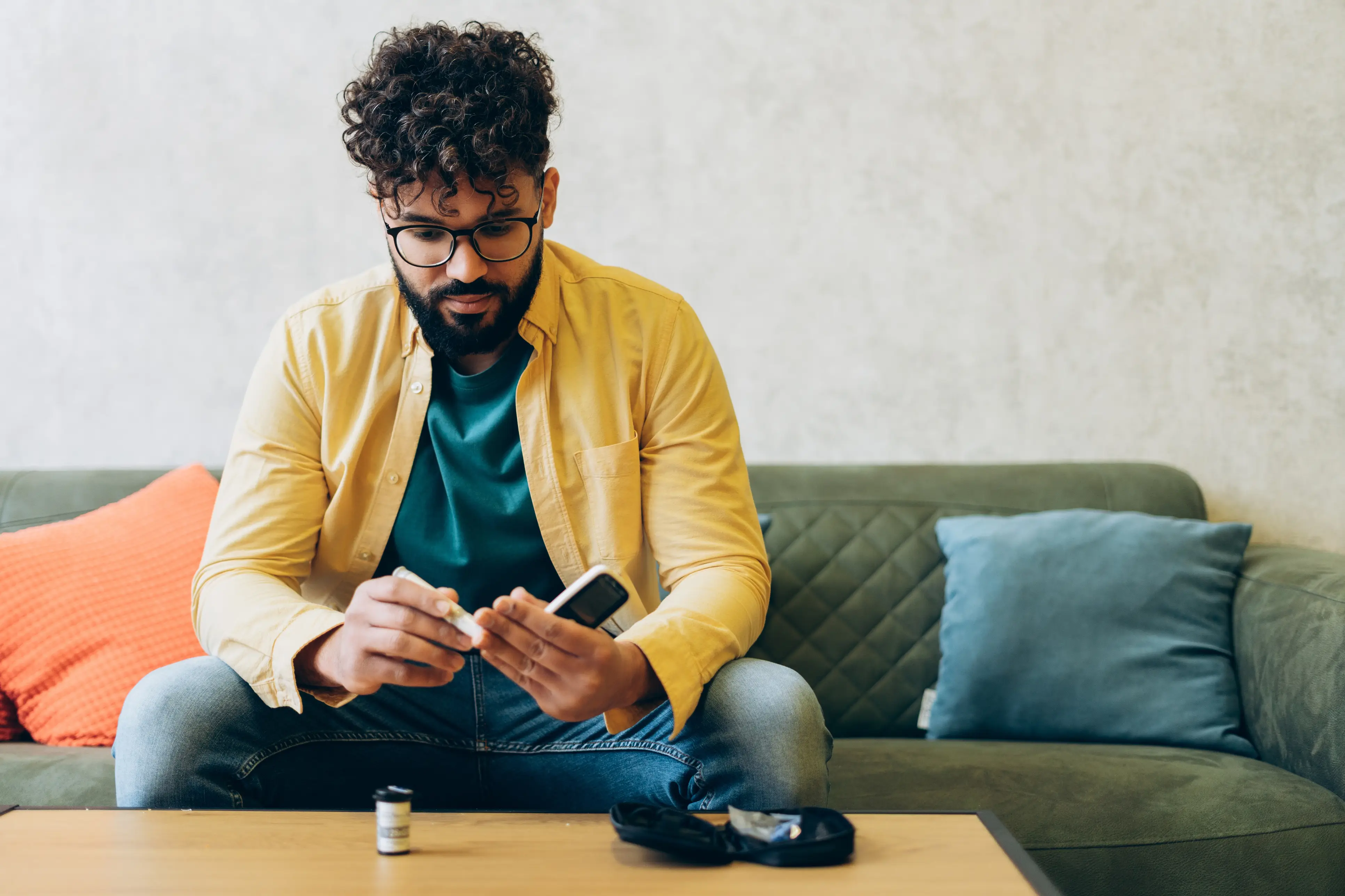 a man sitting on a couch holding a pen and a phone