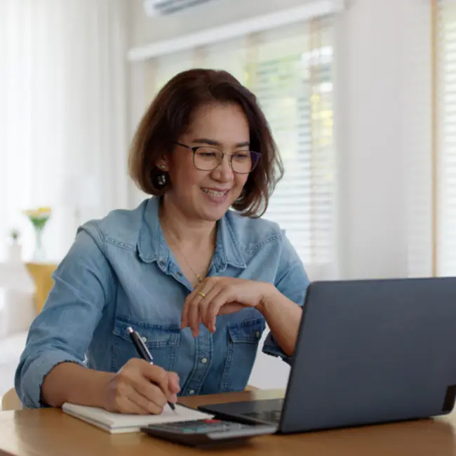 a woman sitting at a desk writing on a notebook