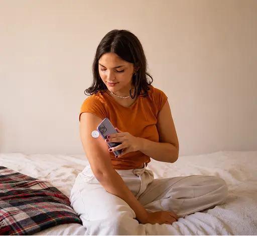 a woman sitting on a bed looking at a cell phone
