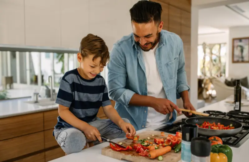 a man and boy cutting vegetables in a kitchen
