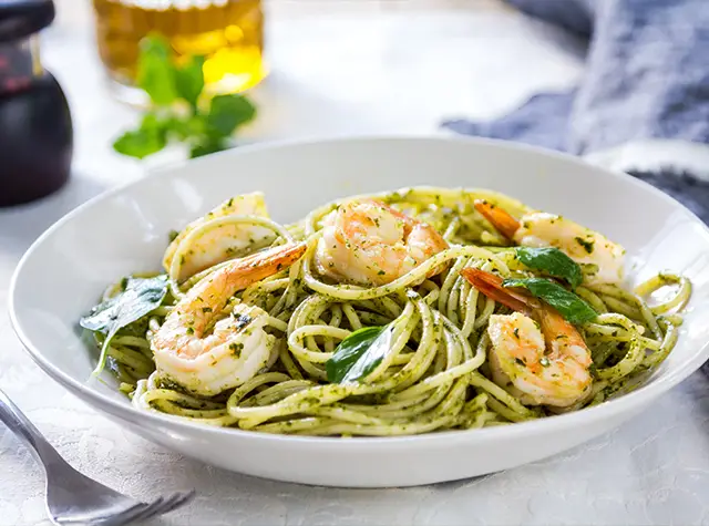 a bowl of pasta with shrimp and basil