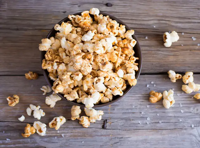 a bowl of popcorn on a wood surface