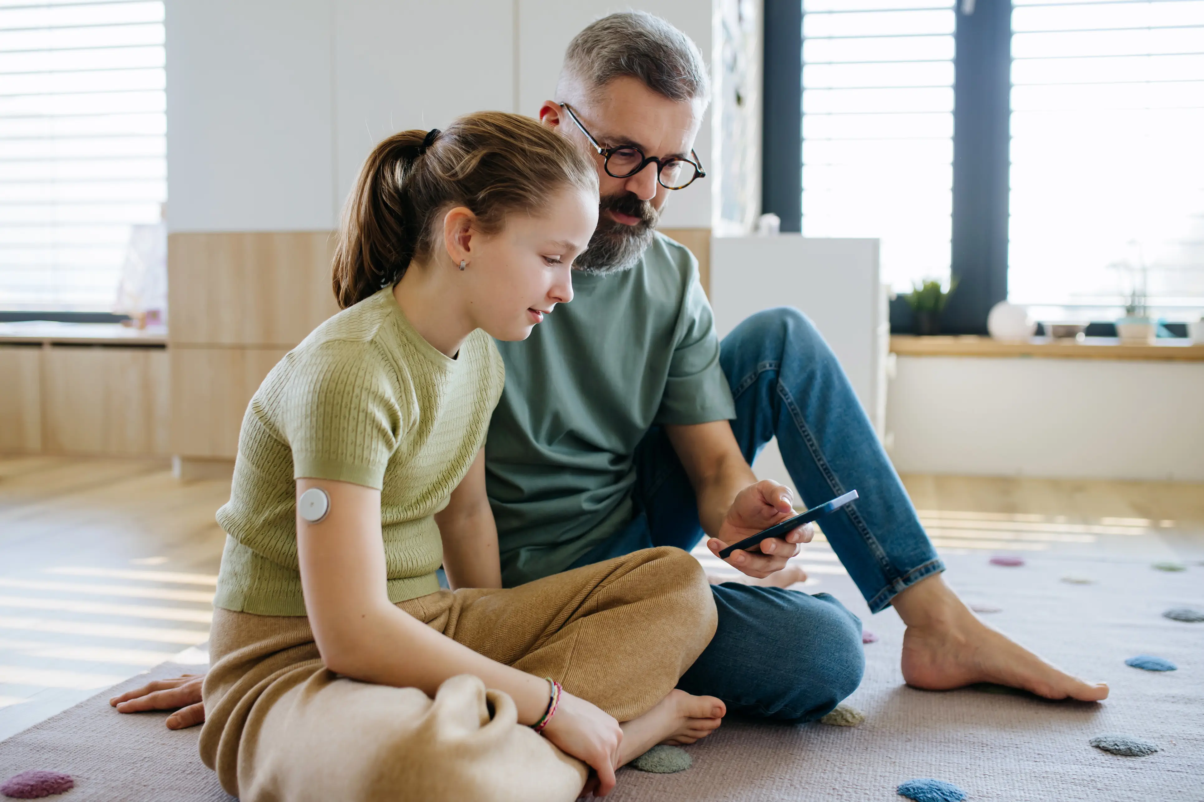 a man and a girl sitting on the floor looking at a phone