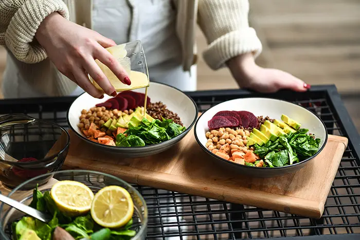a person pouring a liquid into a bowl of food