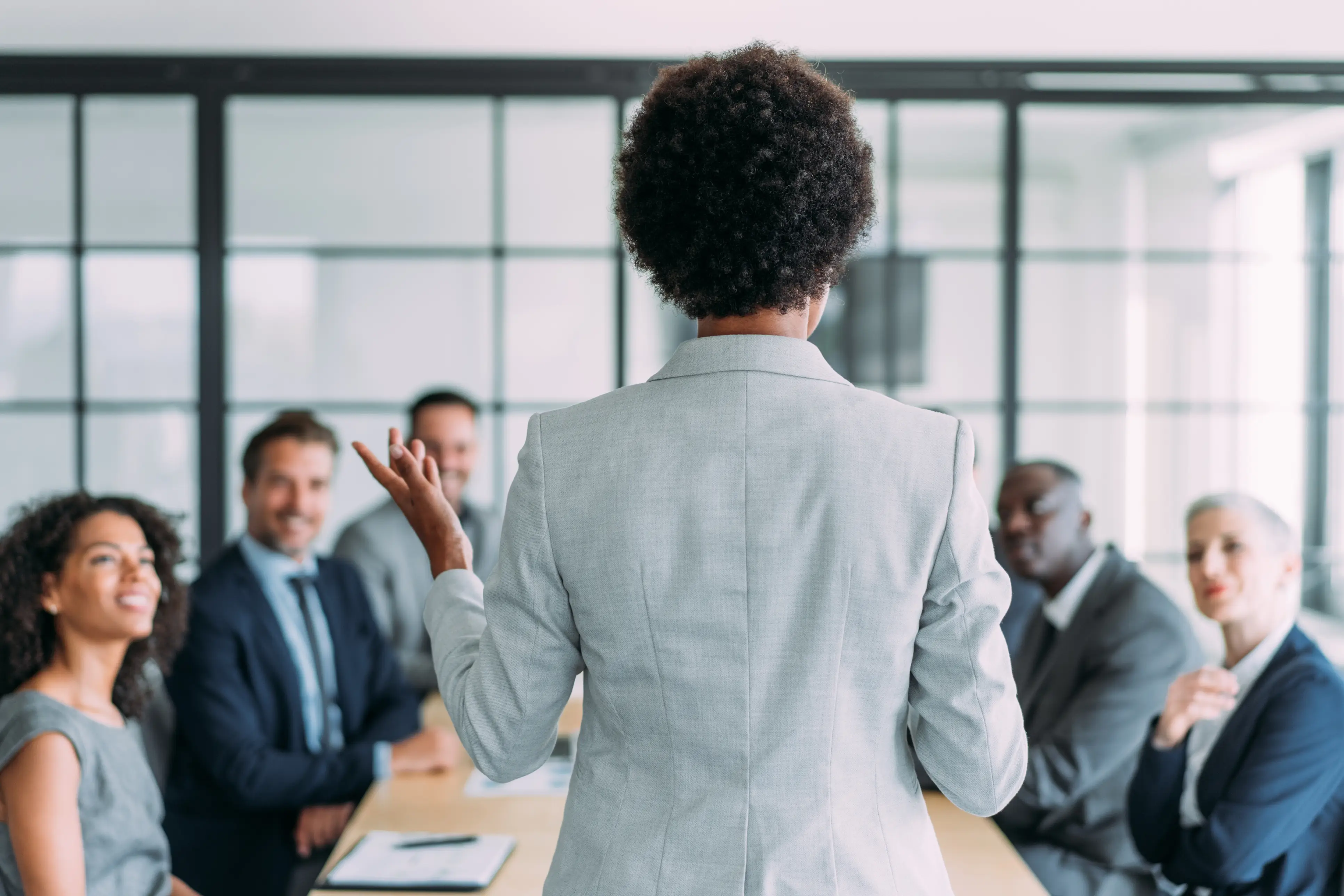 a woman in a suit standing in front of a group of people