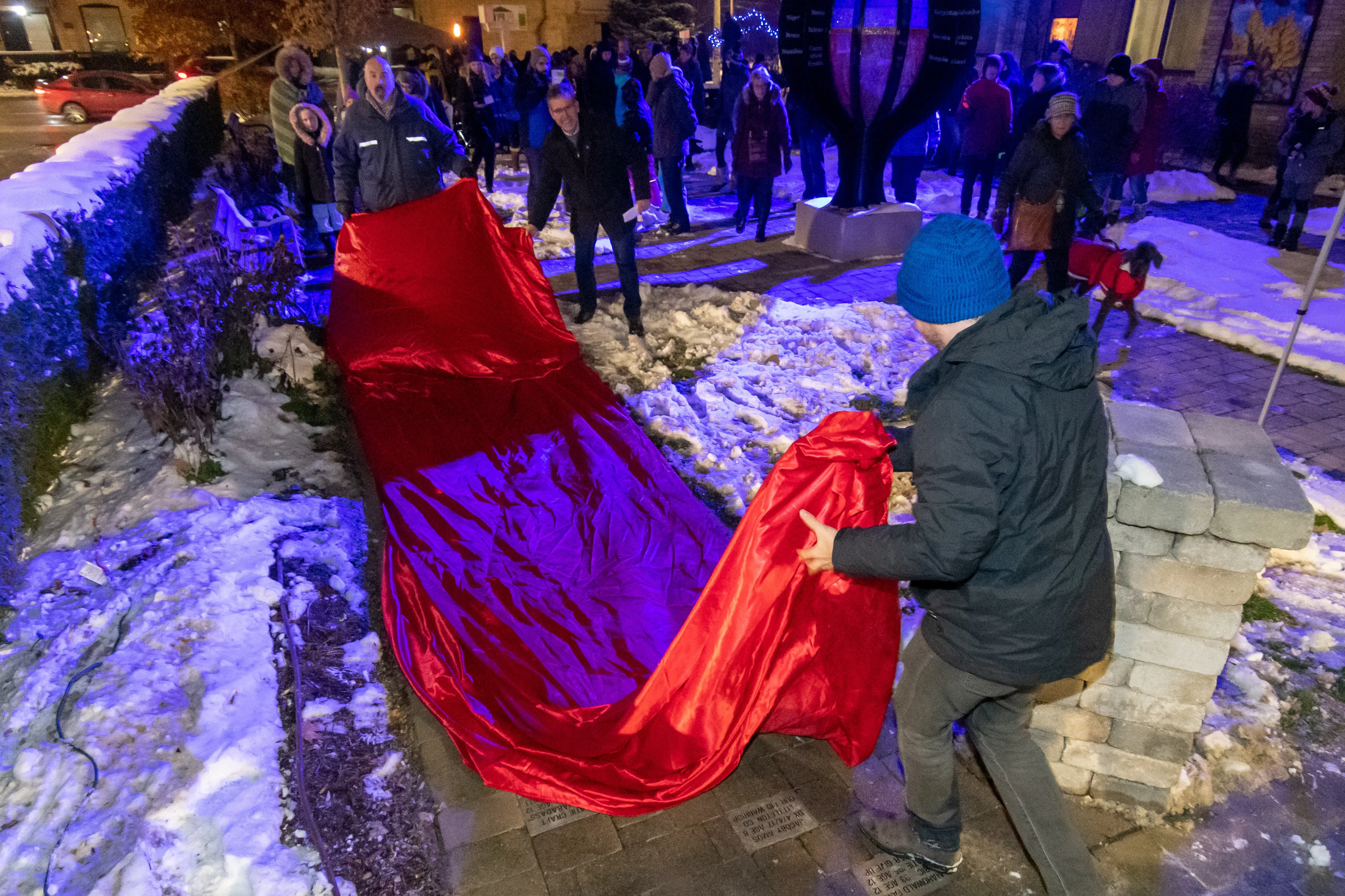 a man rolling a red blanket on a sidewalk