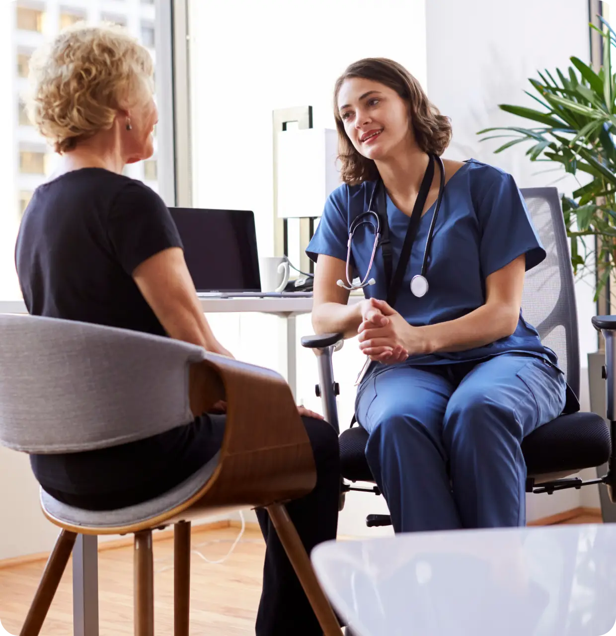 a woman sitting in a chair talking to a doctor