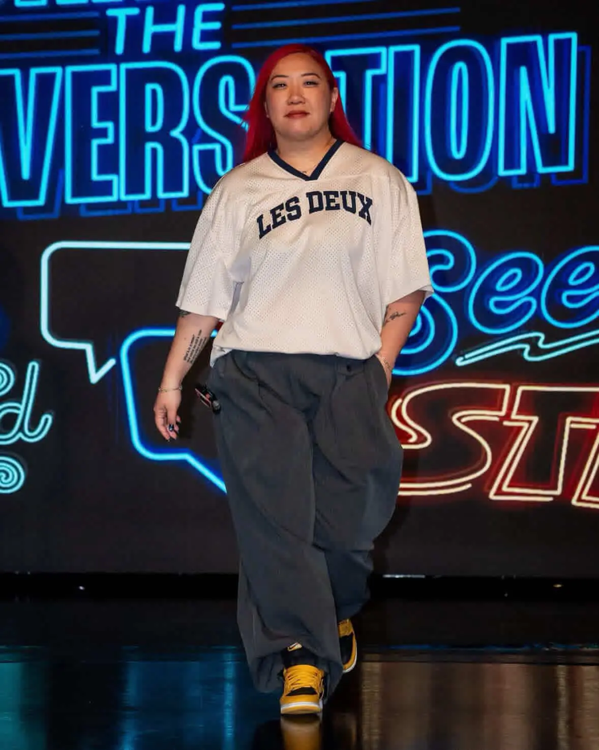 Betsy Cheng on the catwalk a woman with bright red hair is wearing bright yellow sneakers