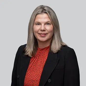Nicole Gourley headshot a smiling woman with shoulder length hair is wearing a red blouse under a black blazer