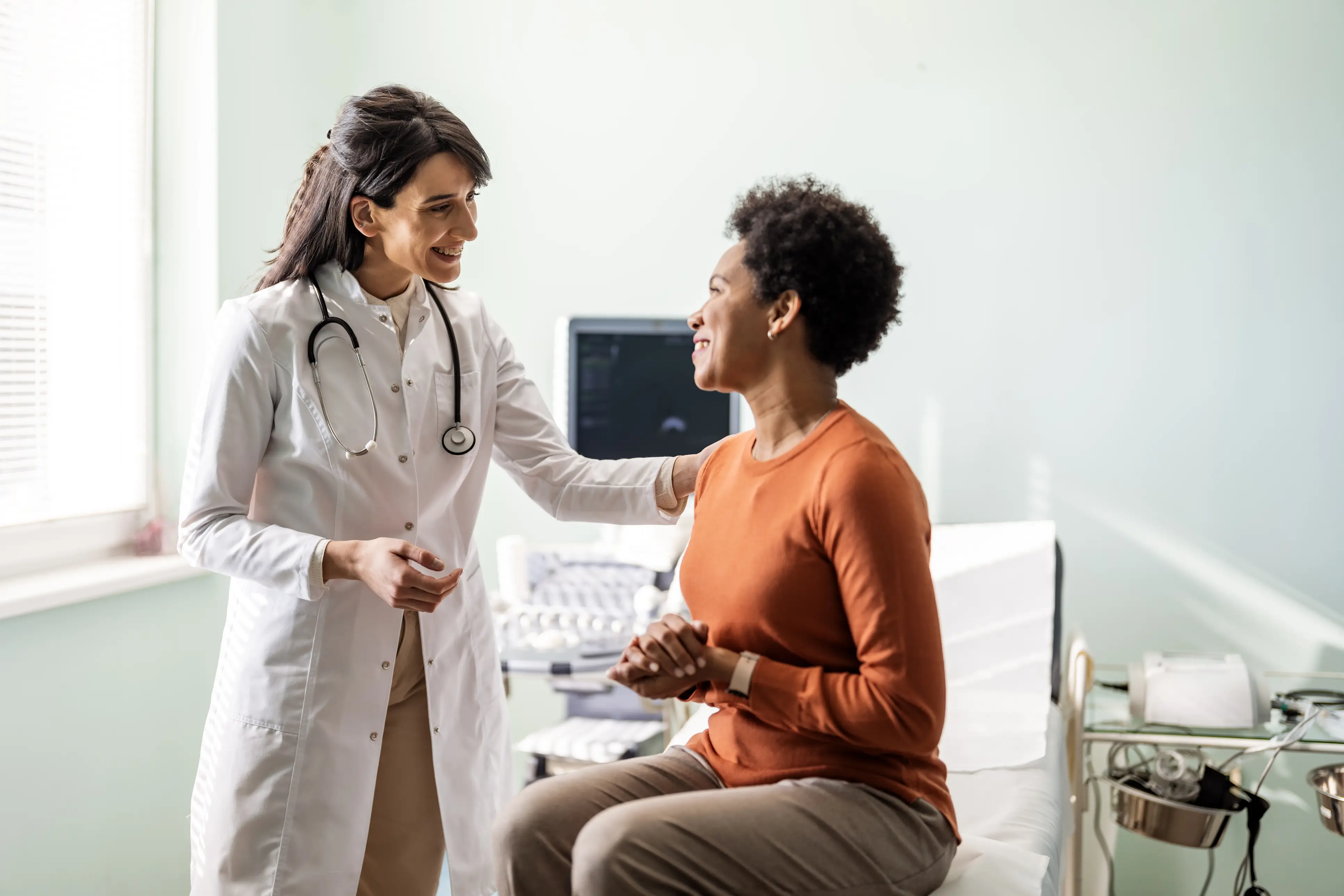 a woman in a white coat talking to a doctor