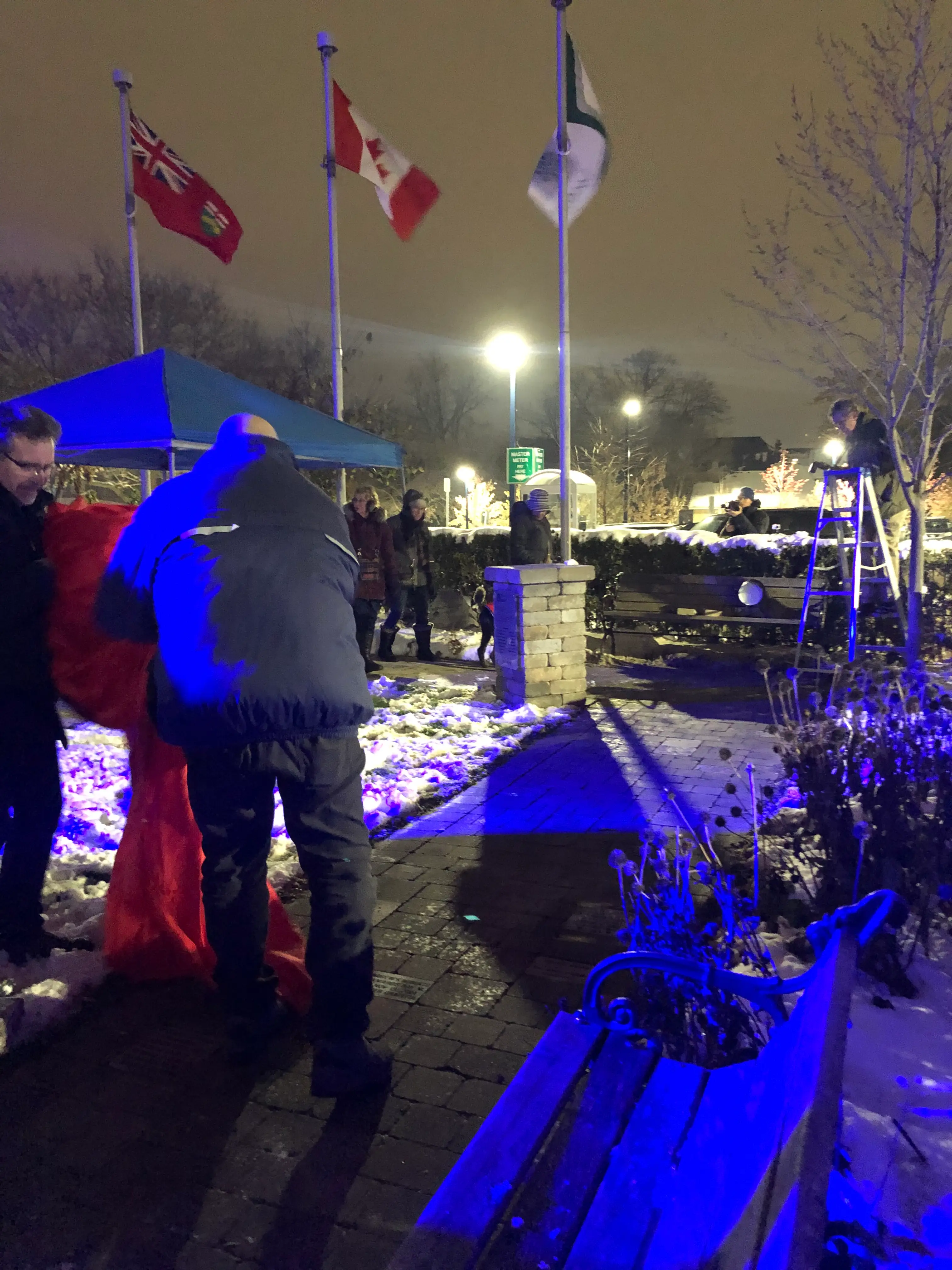 a group of people standing outside with flags and a bench