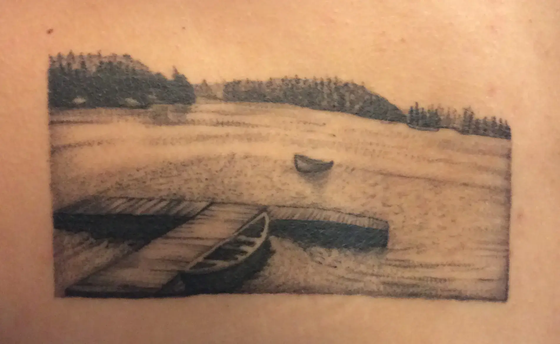 a tattoo of a boat on a body of water