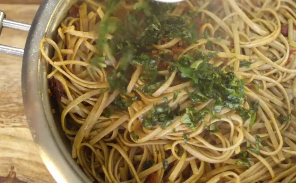 a bowl of noodles with green herbs