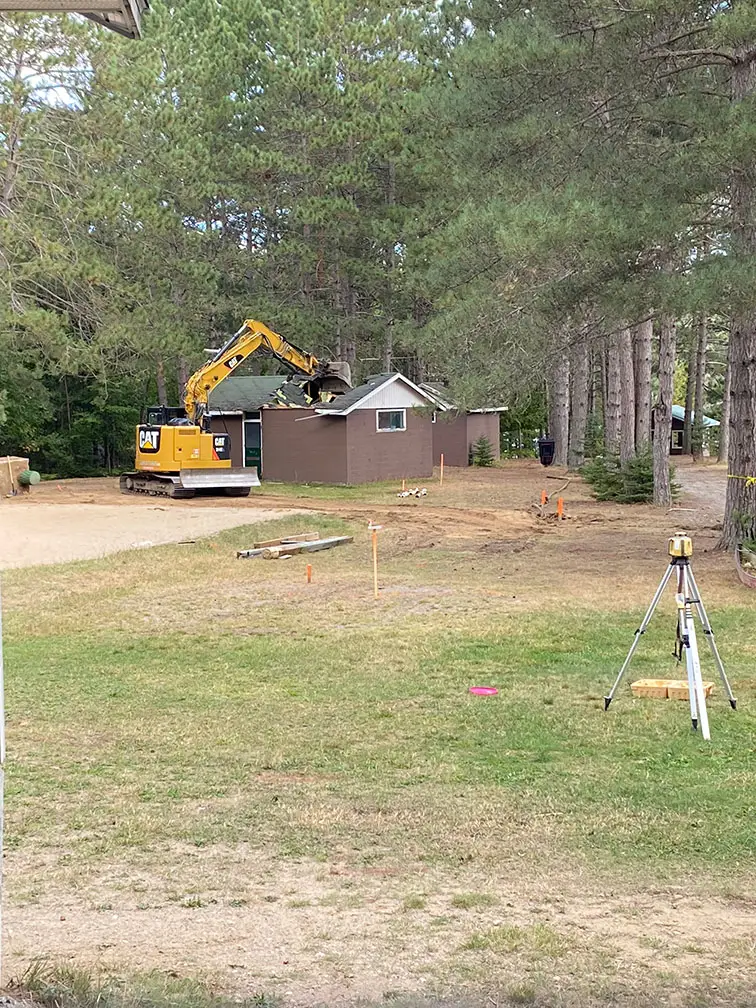 a construction site with a yellow machine and a house