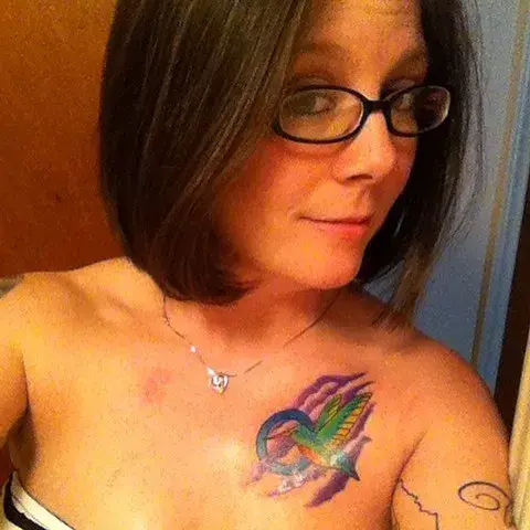 a woman with glasses and a tattoo on her chest