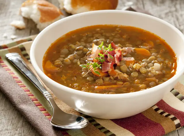 a bowl of soup with a spoon and bread