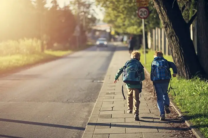 two children walking on a sidewalk