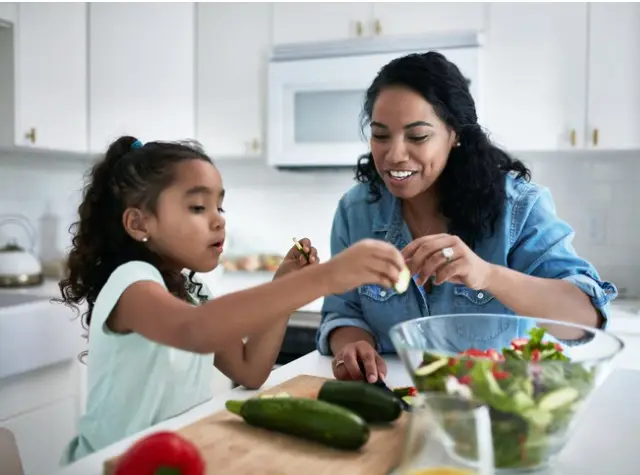 girl-learning-to-prepare-meal-from-mother-picture-id1127294863
