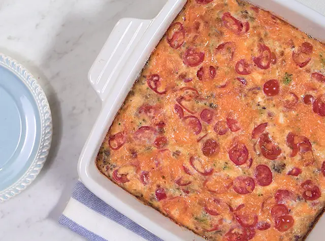 a casserole in a white dish next to a plate of food