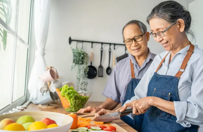 a man and woman in aprons cutting vegetables