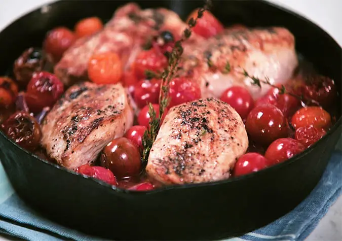 a pan of food with meat and cherry tomatoes