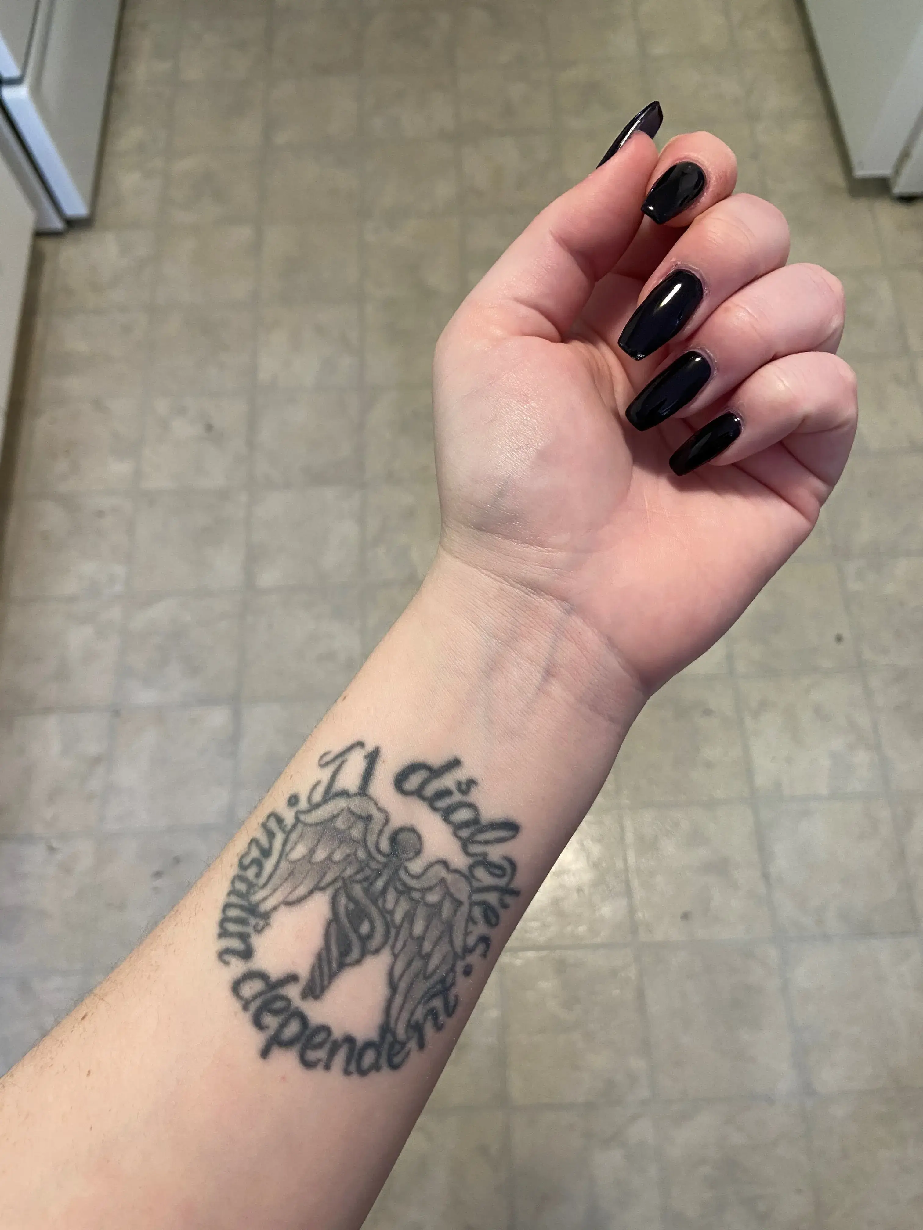 a hand with black nails and a tattoo on it