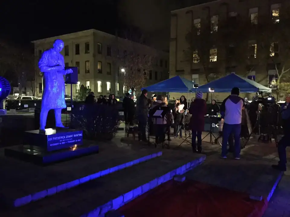 a statue of a man standing on a stage with people around it