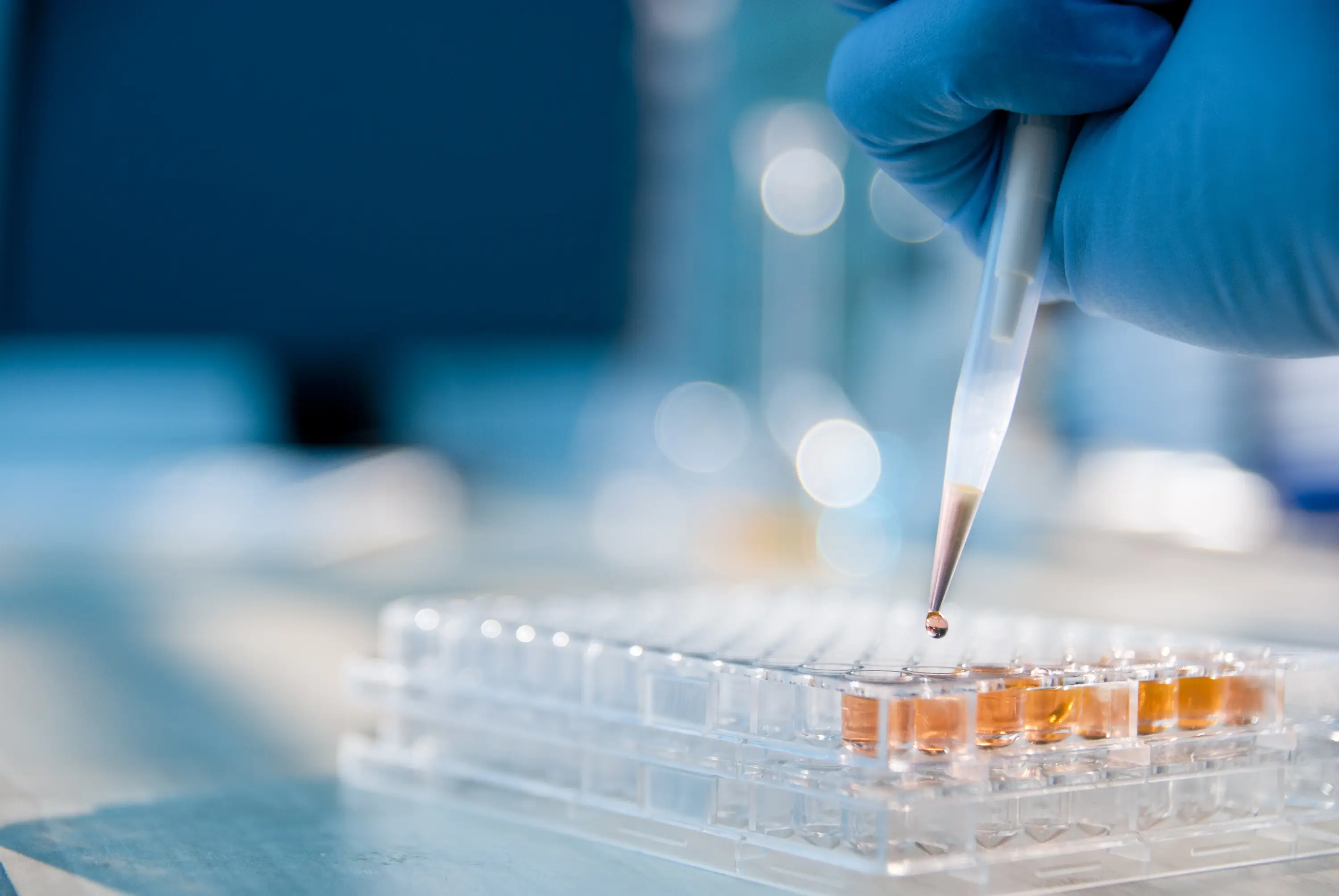 a hand holding a pipette over a test tube