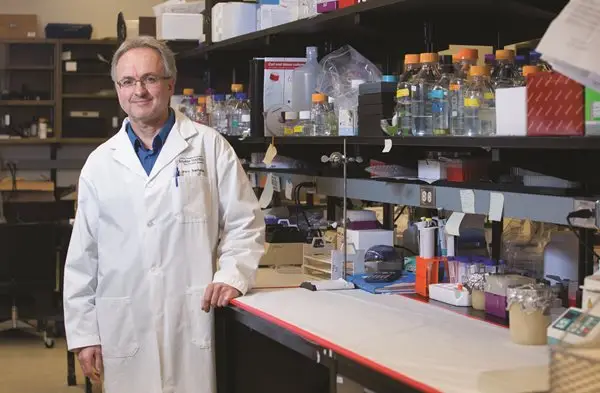 a man in a lab coat standing in front of a shelf with bottles