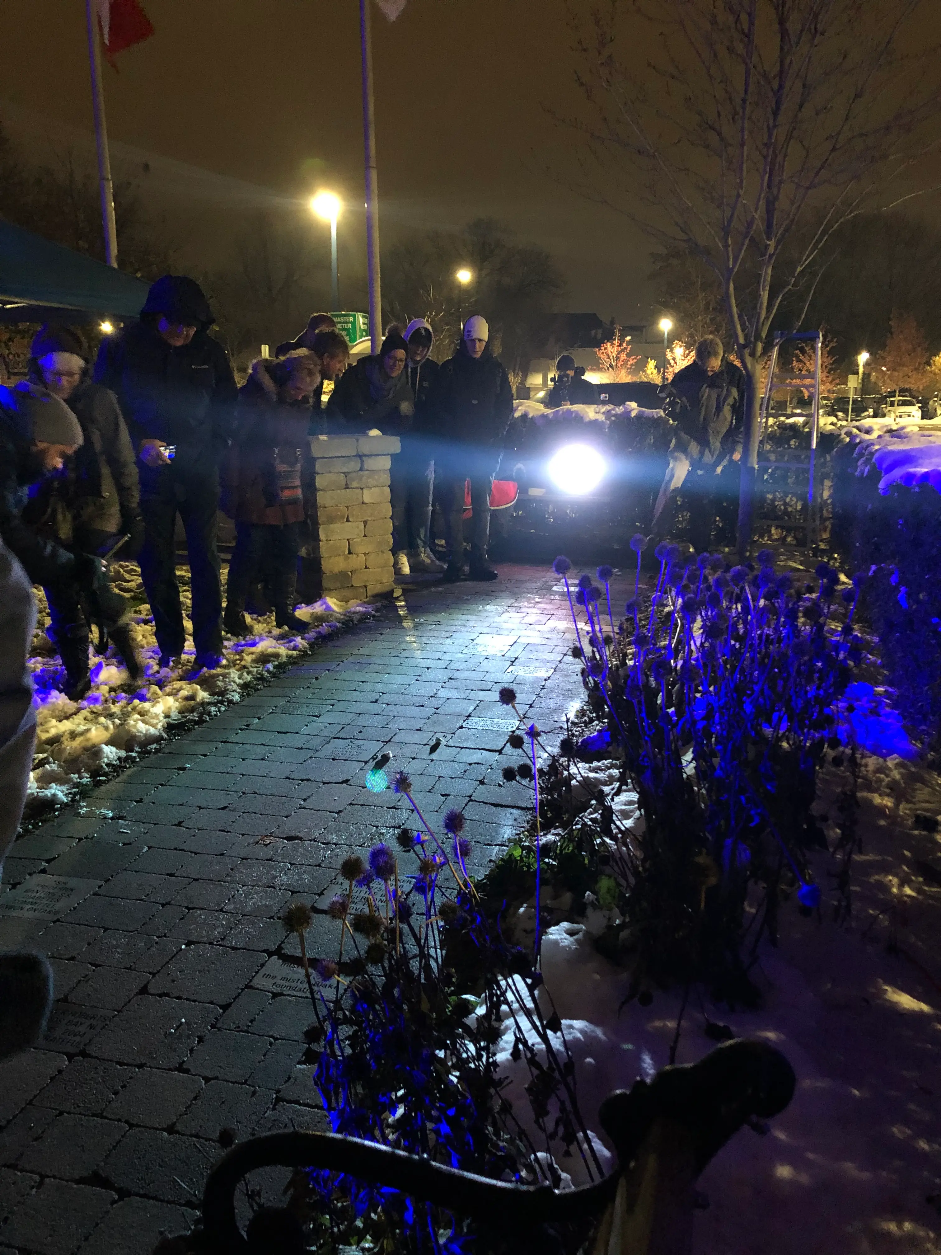 a group of people standing on a brick path with a light on