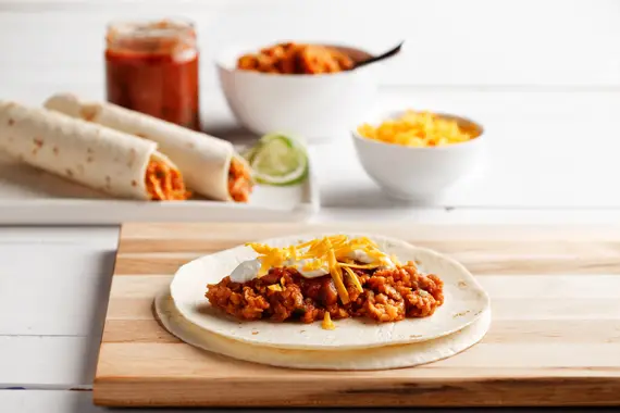a burrito with meat and cheese on a wooden board