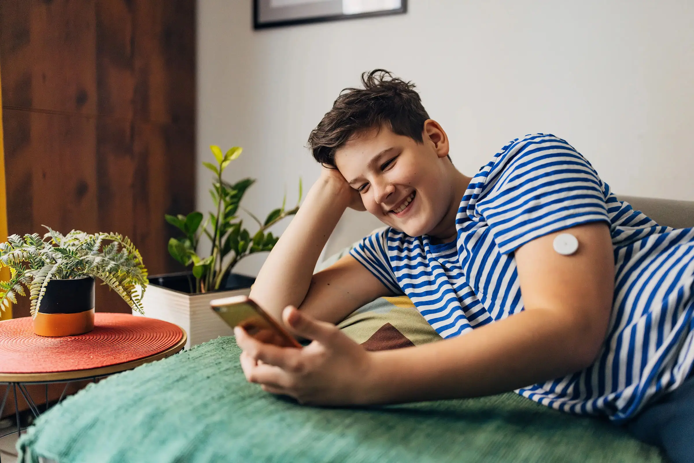 a boy lying on a bed looking at a phone