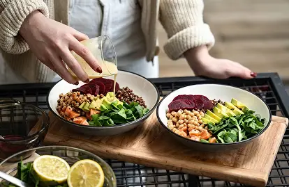 a person pouring a drink into a bowl of food