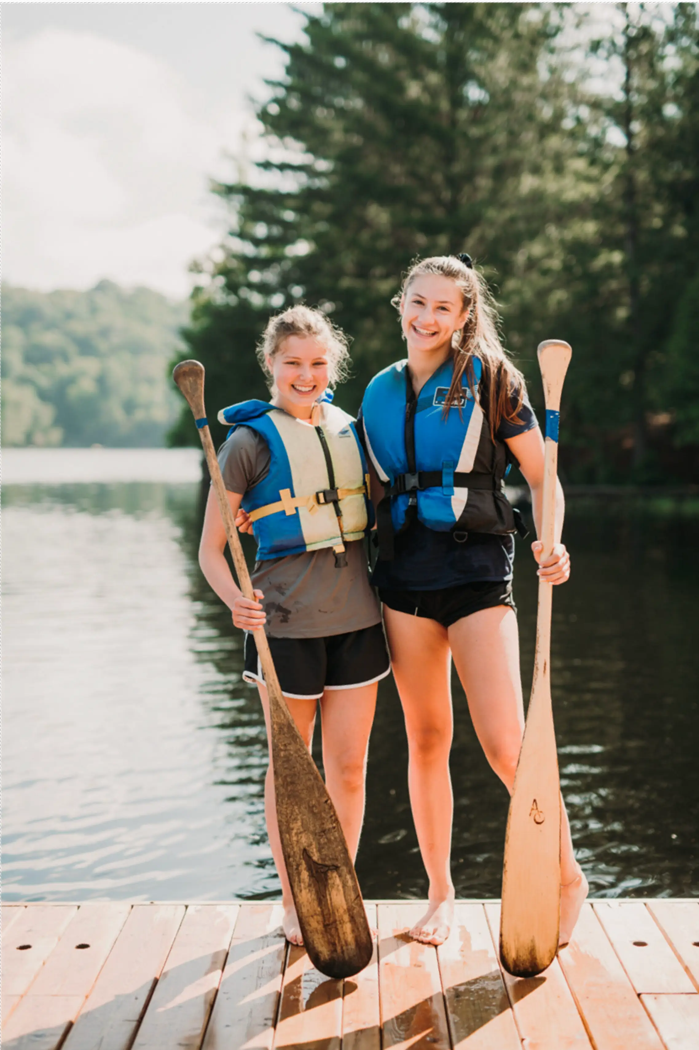 two girls holding paddles in a lake
