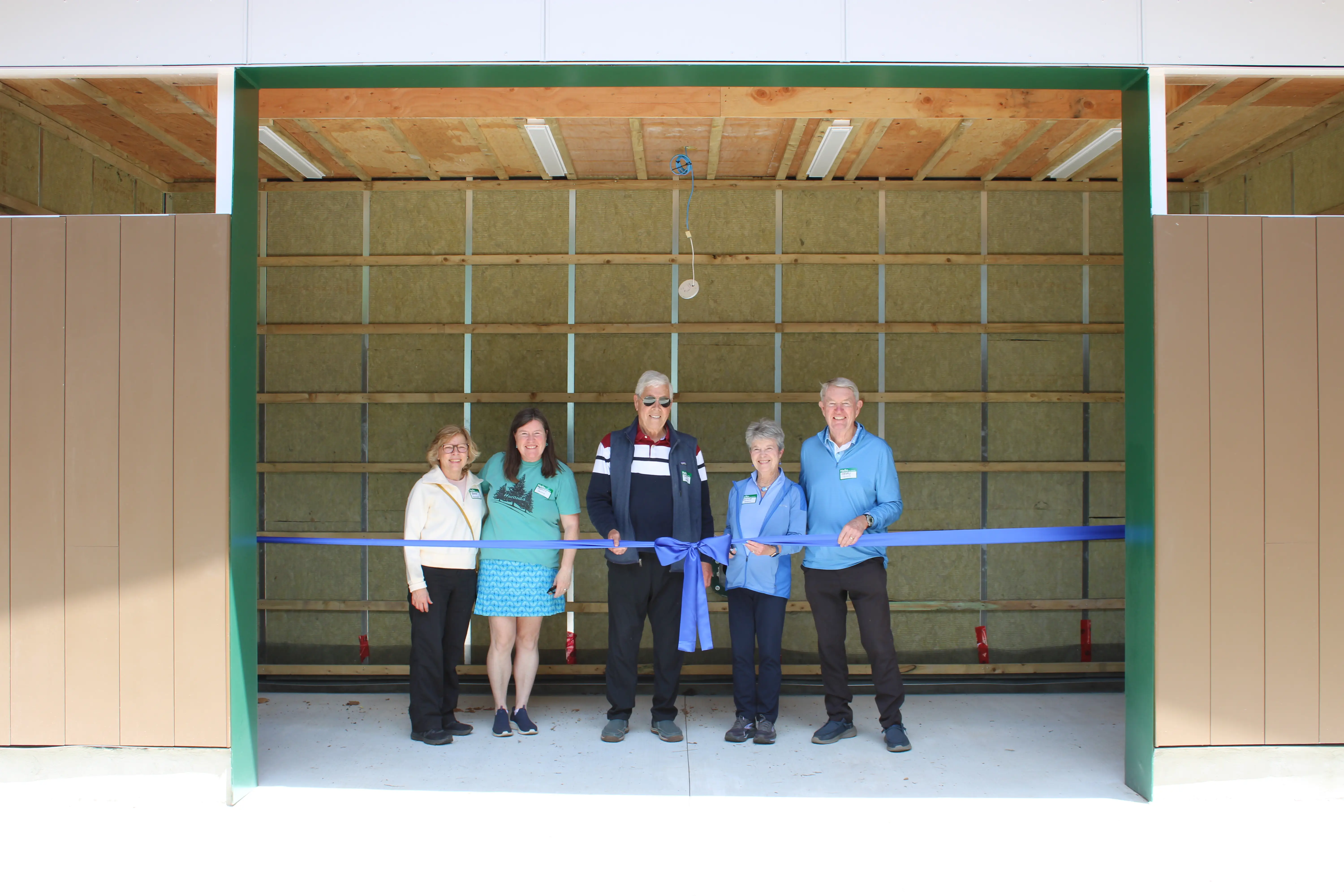 a group of people standing in a garage with a blue ribbon
